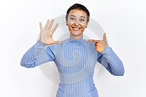 Young hispanic woman with short hair standing over isolated background showing and pointing up with fingers number seven while