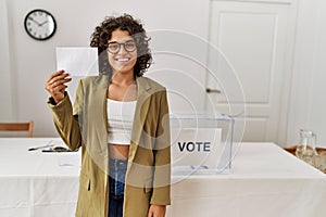 Young hispanic woman smiling confident holding vote at electoral college