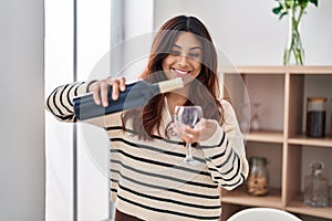 Young hispanic woman smiling confident pouring wine on glass at home