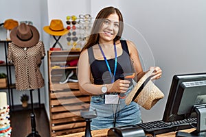 Young hispanic woman smiling confident working at clothing store