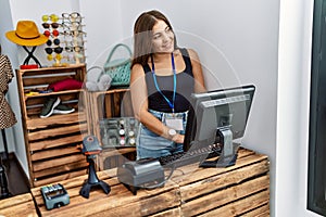 Young hispanic woman smiling confident working at clothing store