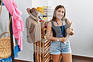 Young hispanic woman smiling confident working at clothing store