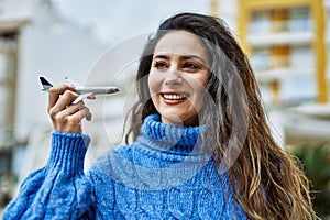 Young hispanic woman smiling happy plane toy at the city