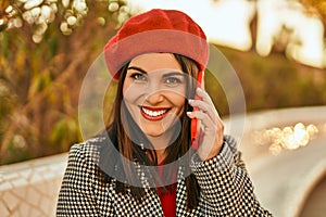 Young hispanic woman smiling happy talking on the smartphone at the park