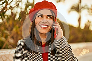 Young hispanic woman smiling happy talking on the smartphone at the park