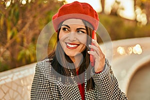 Young hispanic woman smiling happy talking on the smartphone at the park
