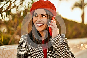 Young hispanic woman smiling happy talking on the smartphone at the park