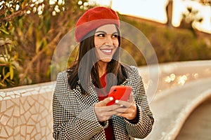 Young hispanic woman smiling happy using smartphone at the park