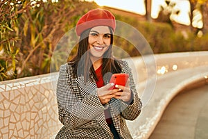 Young hispanic woman smiling happy using smartphone at the park