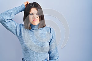 Young hispanic woman standing over blue background confuse and wondering about question