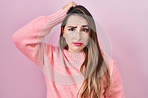 Young hispanic woman standing over pink background confuse and wondering about question