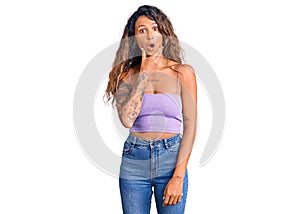 Young hispanic woman with tattoo wearing casual clothes looking fascinated with disbelief, surprise and amazed expression with