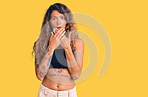 Young hispanic woman with tattoo wearing casual clothes shocked covering mouth with hands for mistake