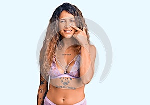 Young hispanic woman with tattoo wearing lingerie pointing with hand finger to face and nose, smiling cheerful