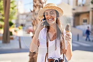 Young hispanic woman tourist talking on the smartphone eating ice cream at street