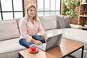 Young hispanic woman using laptop sitting on the sofa at home with a happy and cool smile on face
