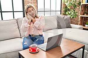 Young hispanic woman using laptop sitting on the sofa at home sleeping tired dreaming and posing with hands together while smiling