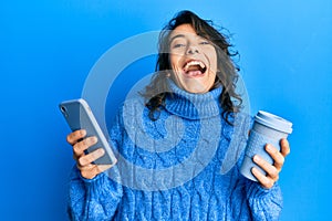 Young hispanic woman using smartphone and drinking a cup of coffee celebrating crazy and amazed for success with open eyes