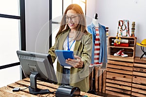 Young hispanic woman using touchpad working at clothing store