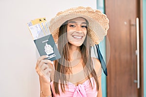 Young hispanic woman on vacation holding canadian passport and boarding pass at street of city