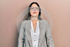 Young hispanic woman wearing business clothes and glasses with serious expression on face