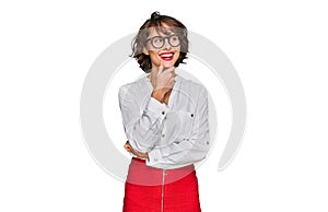 Young hispanic woman wearing business style and glasses with hand on chin thinking about question, pensive expression
