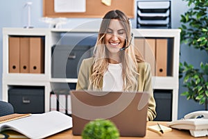 Young hispanic woman wearing call center agent headset working at the office looking positive and happy standing and smiling with