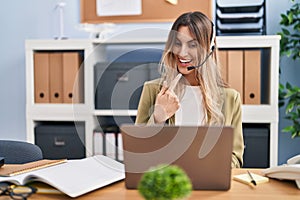 Young hispanic woman wearing call center agent headset working at the office smiling happy pointing with hand and finger