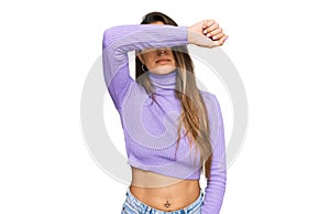 Young hispanic woman wearing casual clothes covering eyes with arm, looking serious and sad