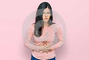 Young hispanic woman wearing casual clothes with hand on stomach because indigestion, painful illness feeling unwell