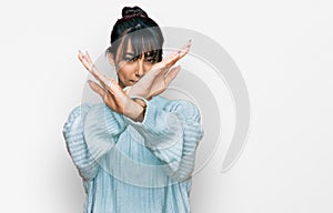 Young hispanic woman wearing casual clothes rejection expression crossing arms and palms doing negative sign, angry face