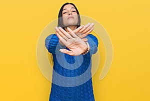 Young hispanic woman wearing casual clothes rejection expression crossing arms and palms doing negative sign, angry face