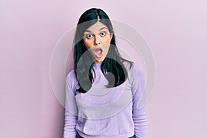 Young hispanic woman wearing casual clothes in shock face, looking skeptical and sarcastic, surprised with open mouth