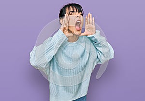 Young hispanic woman wearing casual clothes shouting angry out loud with hands over mouth
