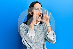 Young hispanic woman wearing casual clothes shouting angry out loud with hands over mouth