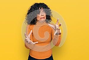 Young hispanic woman wearing casual clothes shouting frustrated with rage, hands trying to strangle, yelling mad