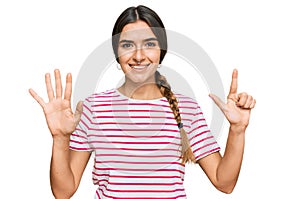 Young hispanic woman wearing casual clothes showing and pointing up with fingers number seven while smiling confident and happy