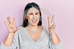 Young hispanic woman wearing casual clothes showing and pointing up with fingers number seven while smiling confident and happy