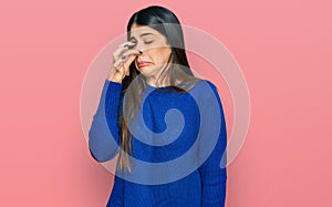 Young hispanic woman wearing casual clothes smelling something stinky and disgusting, intolerable smell, holding breath with