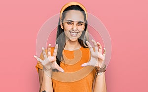 Young hispanic woman wearing casual clothes smiling funny doing claw gesture as cat, aggressive and sexy expression