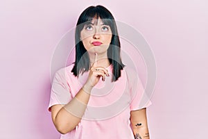 Young hispanic woman wearing casual clothes thinking concentrated about doubt with finger on chin and looking up wondering