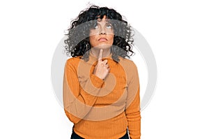 Young hispanic woman wearing casual clothes thinking concentrated about doubt with finger on chin and looking up wondering