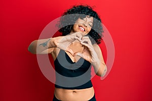Young hispanic woman wearing casual style with sleeveless shirt smiling in love doing heart symbol shape with hands