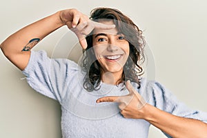 Young hispanic woman wearing casual winter sweater smiling making frame with hands and fingers with happy face