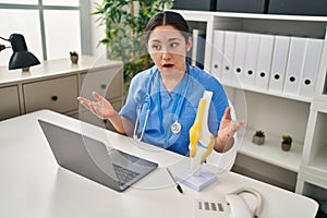 Young hispanic woman wearing doctor uniform having teleconsultation at clinic