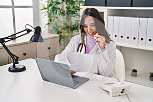 Young hispanic woman wearing doctor uniform having teleconsultation at clinic