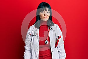 Young hispanic woman wearing doctor uniform and stethoscope looking sleepy and tired, exhausted for fatigue and hangover, lazy