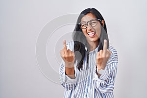 Young hispanic woman wearing glasses showing middle finger doing fuck you bad expression, provocation and rude attitude