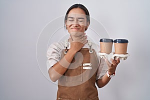 Young hispanic woman wearing professional waitress apron holding coffee touching painful neck, sore throat for flu, clod and