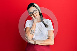 Young hispanic woman wearing professional waitress apron thinking looking tired and bored with depression problems with crossed